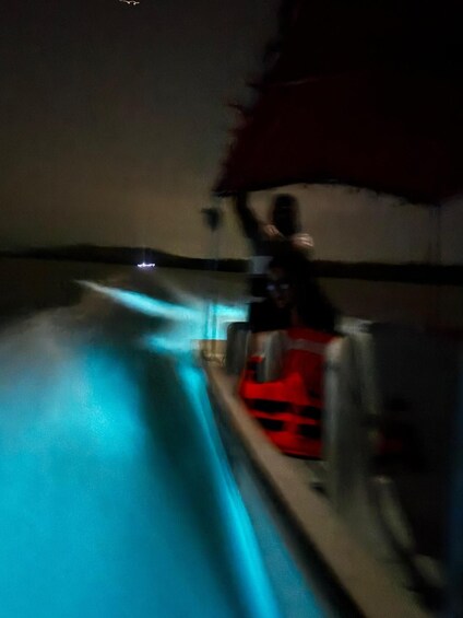 A person riding a jet ski on a body of water at night. 5