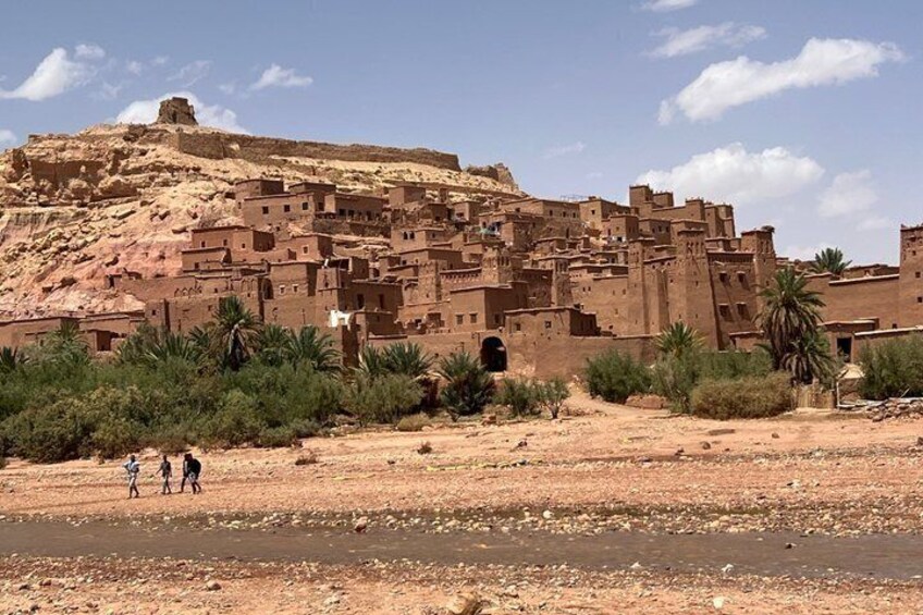 A desert landscape with a large, ancient walled city and a small body of water. 1