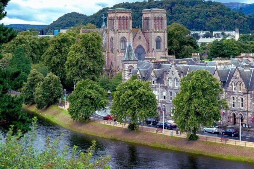 A historic church with twin towers, surrounded by trees and a river. 1
