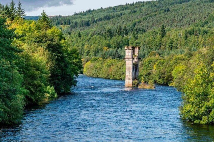 A river with a stone tower in the center, surrounded by dense forest. 4