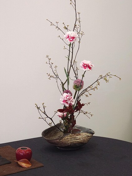 A floral arrangement in a rustic ceramic bowl on a dark surface. 1