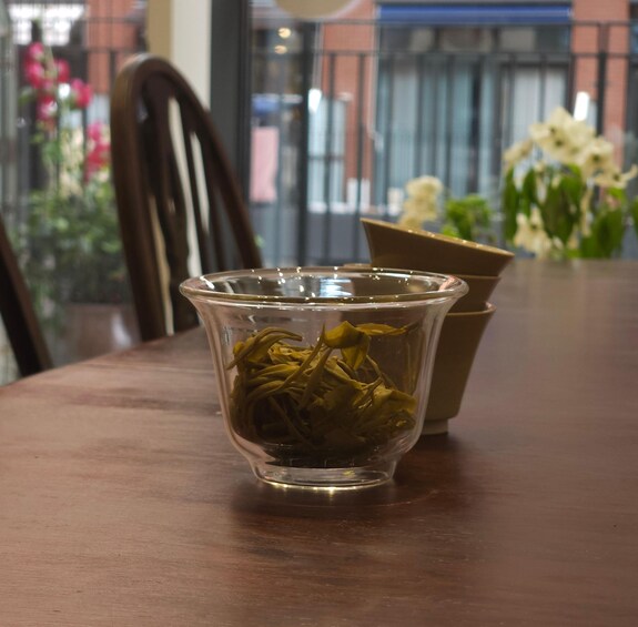 A glass cup filled with green tea on a wooden table. 5