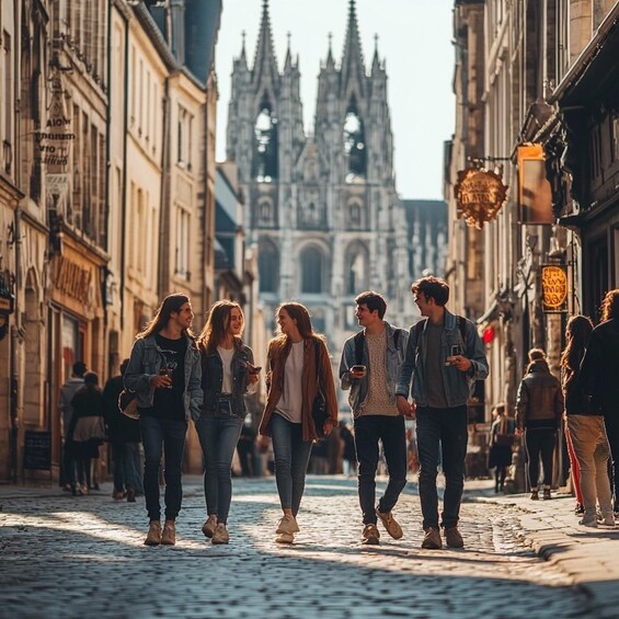 A cobblestone street lined with historic buildings and a Gothic cathedral in the background. 1