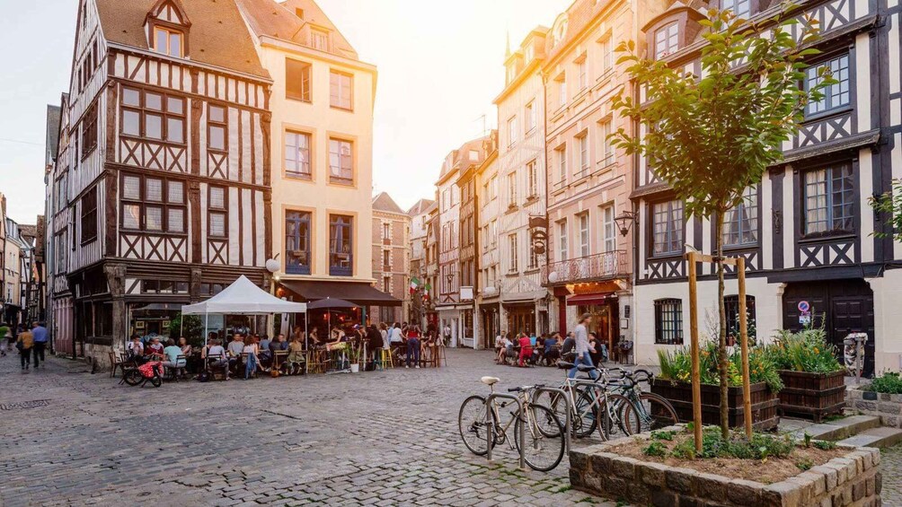 A cobblestone street with traditional half-timbered buildings, outdoor seating, and bicycles. 4