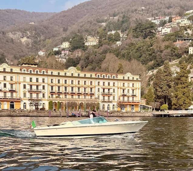 A boat on a calm lake with a row of buildings in the background. 3