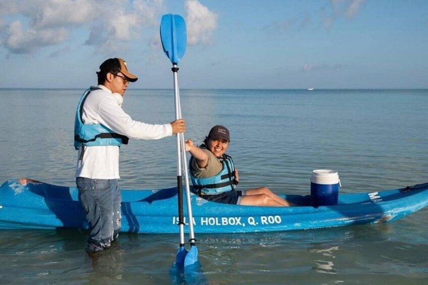 Two people in a blue kayak on calm water, one paddling. 3