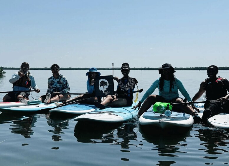 A group of people sitting on paddleboards on a calm lake. 2