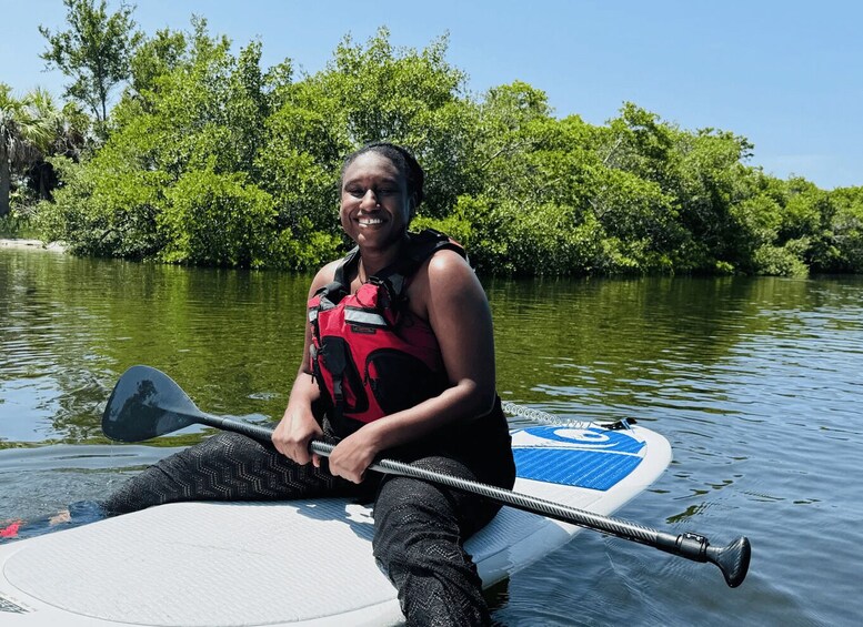 A person sitting on a paddleboard in a river surrounded by lush greenery. 3