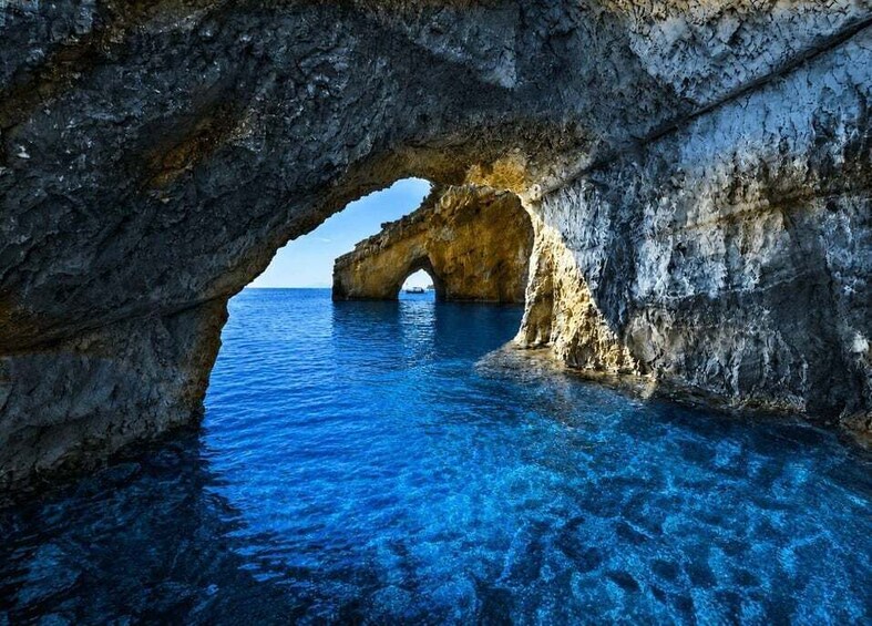 A natural rock arch over clear blue water. 2