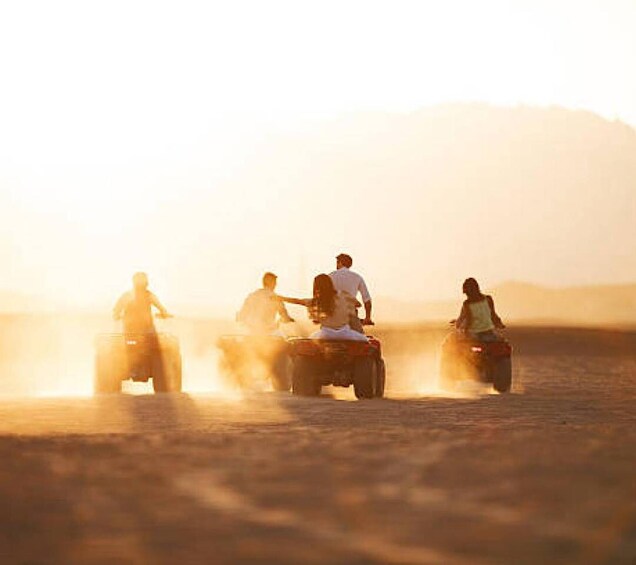 A group of people riding atv's in a desert landscape. 4