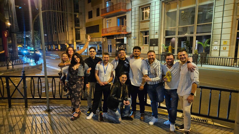 A group of people posing on a city sidewalk at night. 4