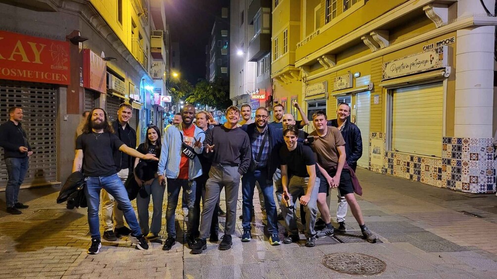 A group of people posing on a city street at night. 3