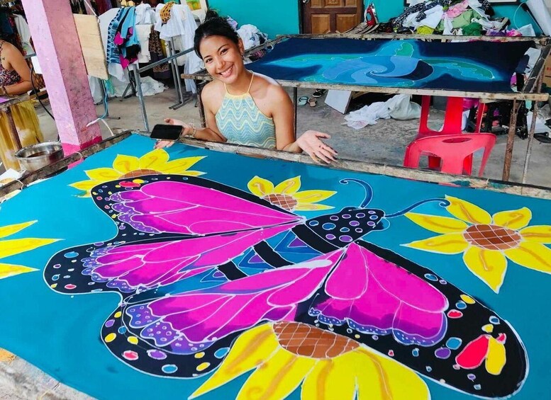 A person standing in front of a large, colorful mural featuring a butterfly and flowers. 3