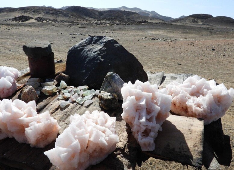 A desert landscape with large pink salt formations and a dark rock in the background. 3