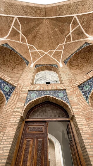 A mosque interior with brick arches, a wooden door, and intricate tile work. 3