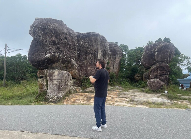 A person standing on a road with large rock formations in the background. 2