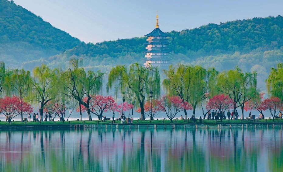 A serene lake with a pagoda in the background, surrounded by trees with pink blossoms. 3