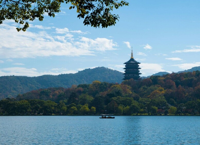 A pagoda on a hill with a boat on the water. 2