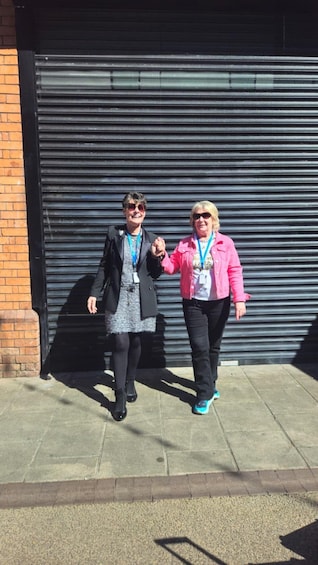Two people walking in front of a closed metal shutter door. 3