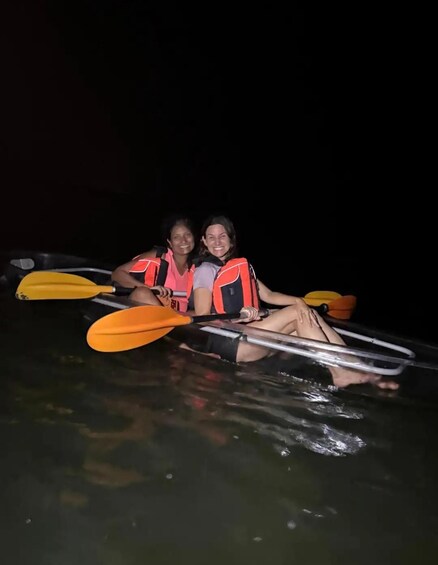 Two people in a kayak on a body of water at night. 5