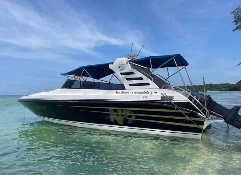 A speedboat with a blue canopy and a black and white hull, floating on clear turquoise water. 2