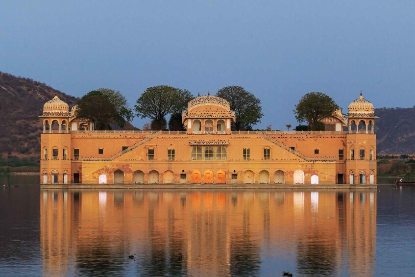 A large, ornate building with domed structures and arched windows, reflecting on a calm body of water. 4