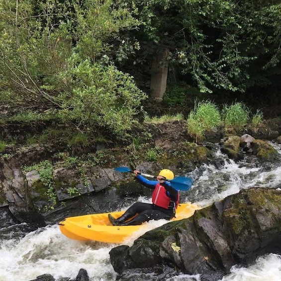 A person kayaking on a river surrounded by greenery. 1