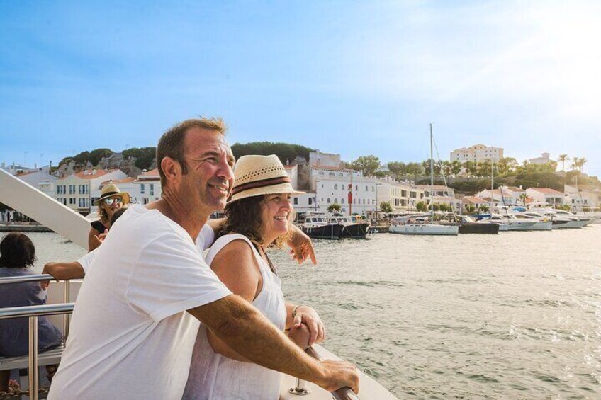 A couple on a boat with a marina and buildings in the background. 5