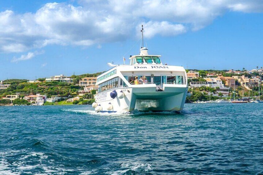 A white boat named 'Don Joan' on the water with a coastal town in the background. 4