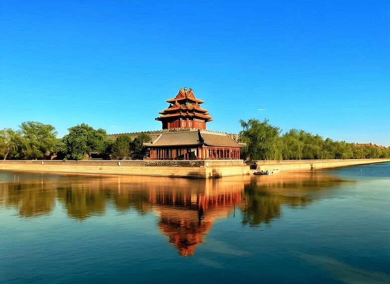 A traditional Chinese pagoda by a calm river with clear blue skies. 2