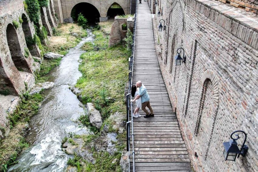 A wooden bridge over a river in an old stone building with arched passageways. 4