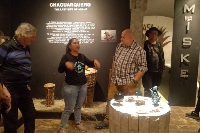 A museum exhibit with a display table, informational text, and a wall with a name. 4