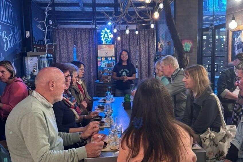 A group of people seated around a table in a restaurant with a city view. 2