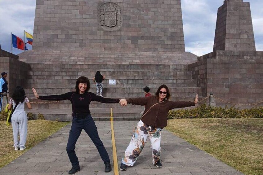 Two people holding hands in front of a large stone monument with flags in the background. 1
