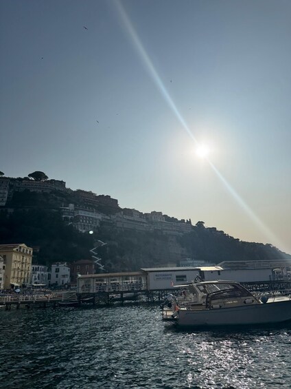 A boat docked at a marina with buildings and a hill in the background. 5