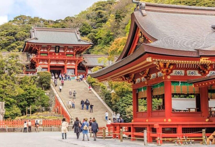 A traditional Japanese temple with a red torii gate, a staircase leading up to the main building, and lush greenery in the background. 5