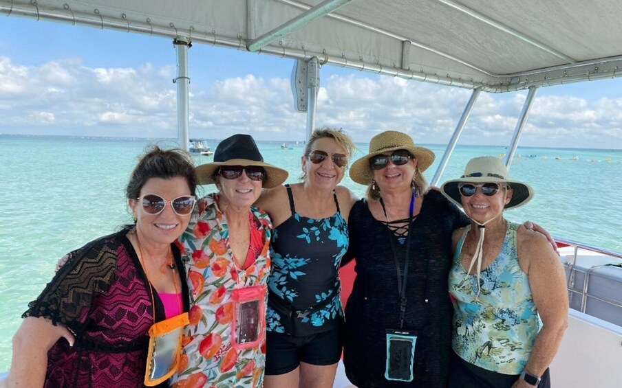 A group of people on a boat with a clear blue sea and a white boat canopy. 3