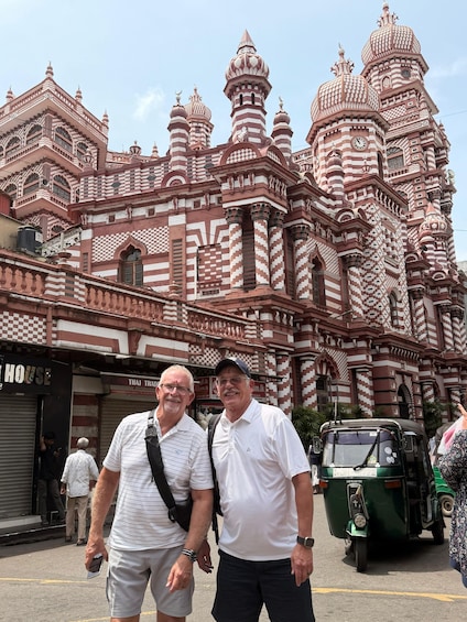 A man and woman standing in front of a large, ornate building with intricate patterns and domes. 2