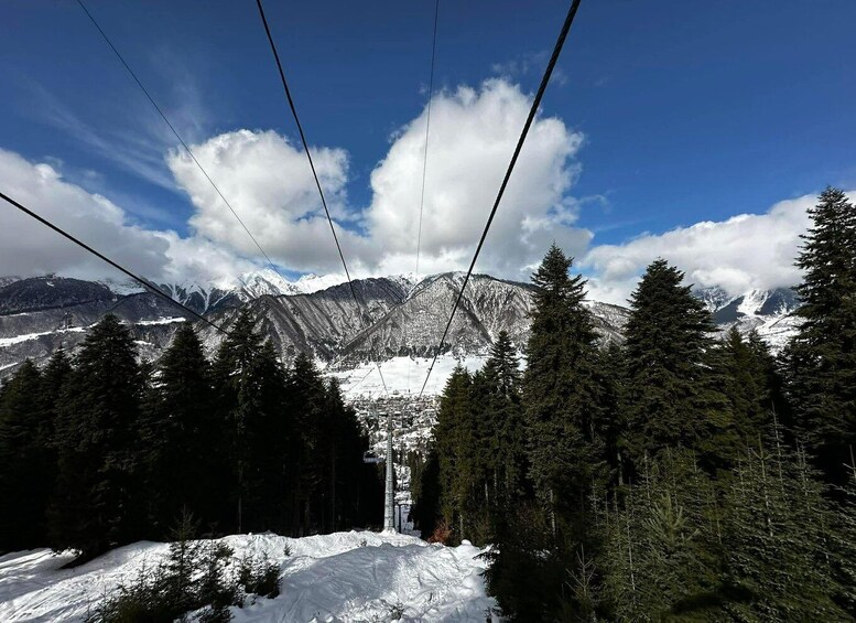 A snowy mountain landscape with a ski lift, evergreen trees, and a clear blue sky. 2