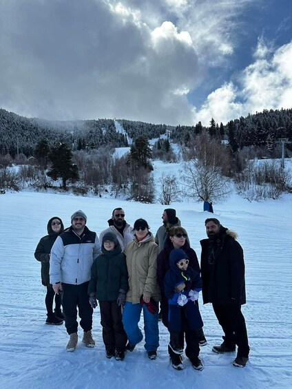 A group of people standing on a snow-covered field with a forested mountain in the background. 5