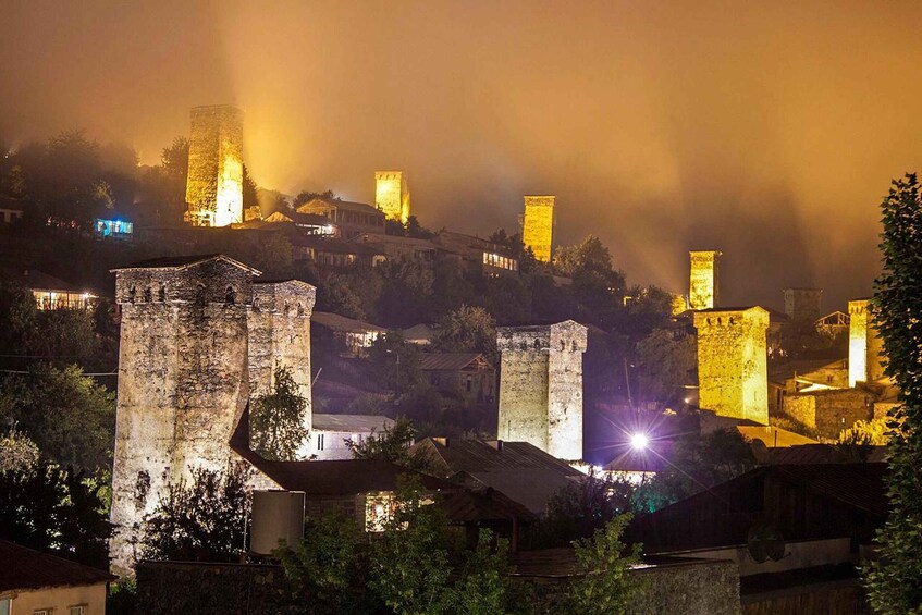 A historic town with illuminated towers and buildings at night. 1