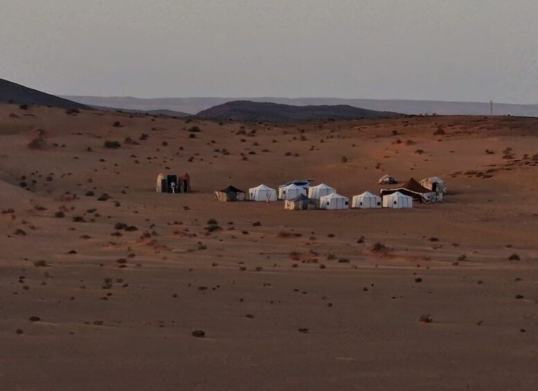 A desert landscape with several white tents and a few small buildings. 5