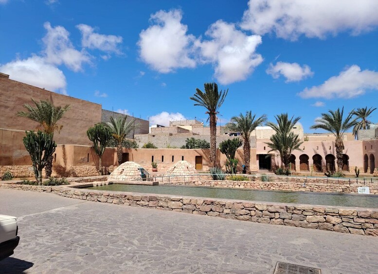 A courtyard with palm trees, a water feature, and traditional architecture. 1