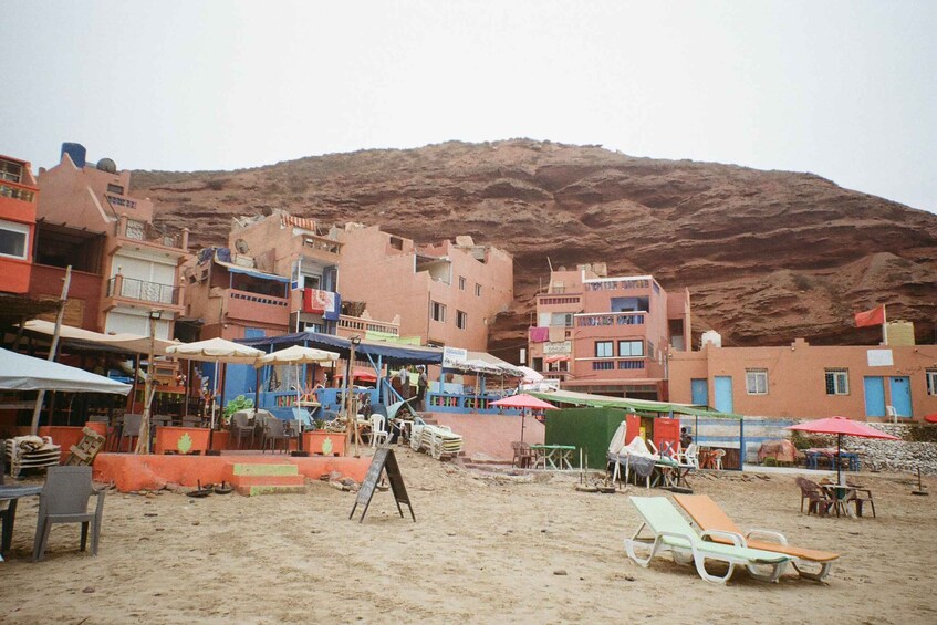 A sandy beach with colorful buildings and a mountain in the background. 3