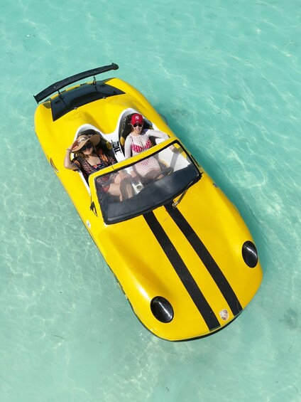 A yellow boat with black stripes floating on clear turquoise water. 2