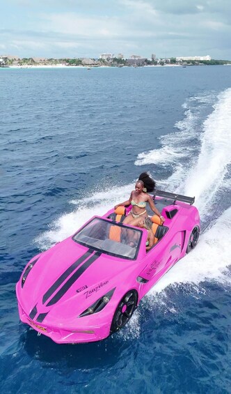 A pink speedboat with a person on it, moving through a body of water with a distant shoreline. 1