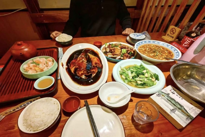 A wooden table with various dishes, including a bowl of rice, a plate of shrimp, and a bowl of soup. 5