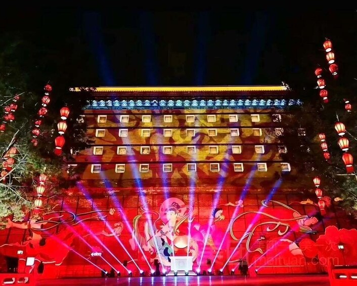 A brightly lit stage with a traditional building backdrop, red lanterns, and colorful laser lights. 5