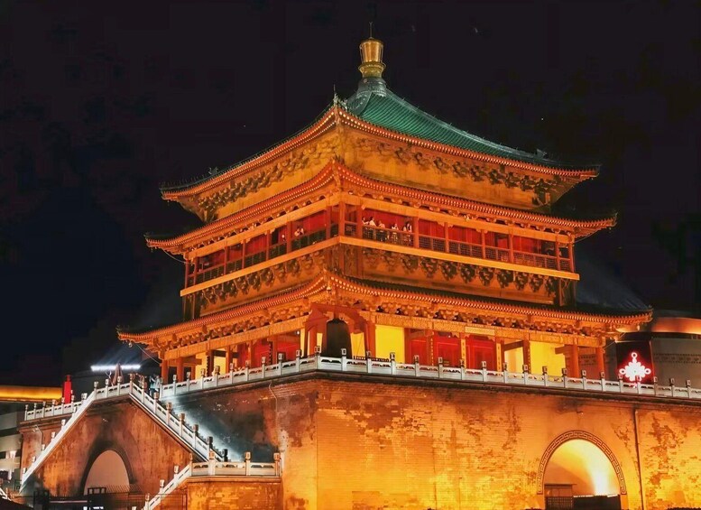 A multi-tiered traditional Chinese building with ornate detailing and a green roof, illuminated at night. 4