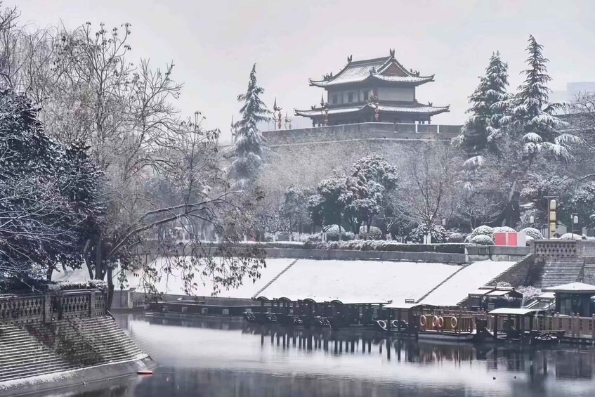 A snow-covered landscape with traditional architecture, a frozen lake, and a bridge. 1